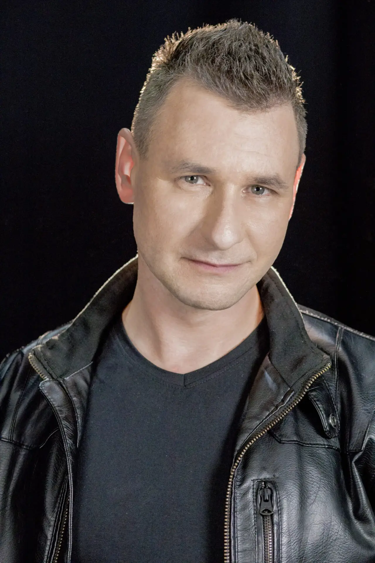 Portret artystyczny mężczyzny w skórzanej kurtce na czarnym tle