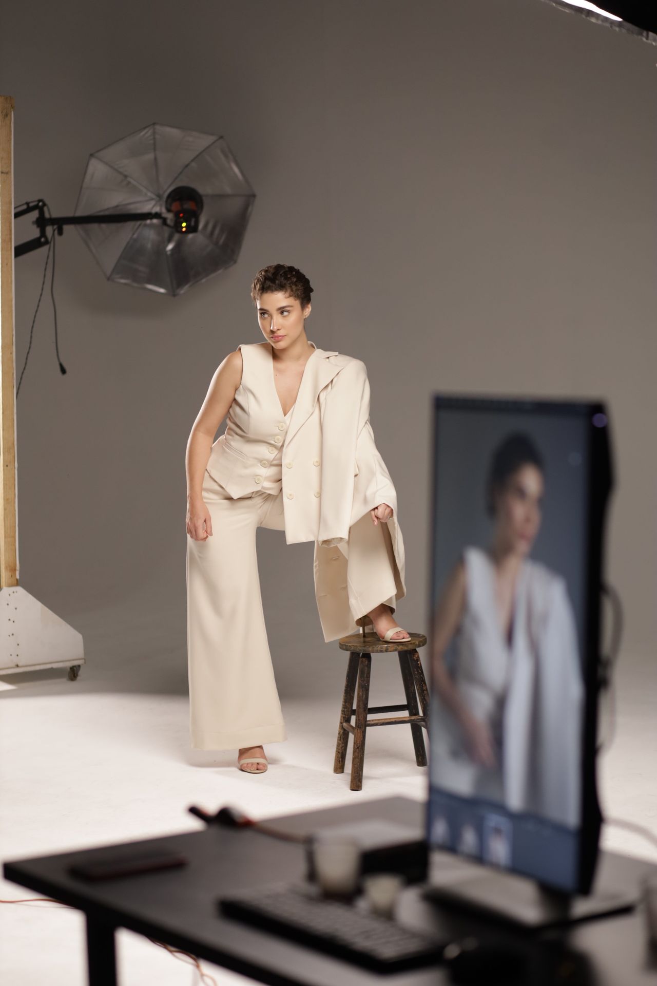 Modelka w jasnym kostiumie pozująca w studiu fotograficznym — zdjęcie ilustracyjne
